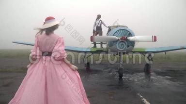 一位60岁的女士穿着粉色连衣裙来到一架老式<strong>飞机上</strong>，<strong>飞机上</strong>站着飞行员